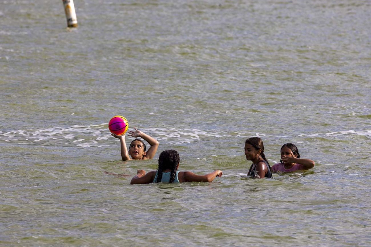 Kids swimming and playing in the water. One of the kids have a ball