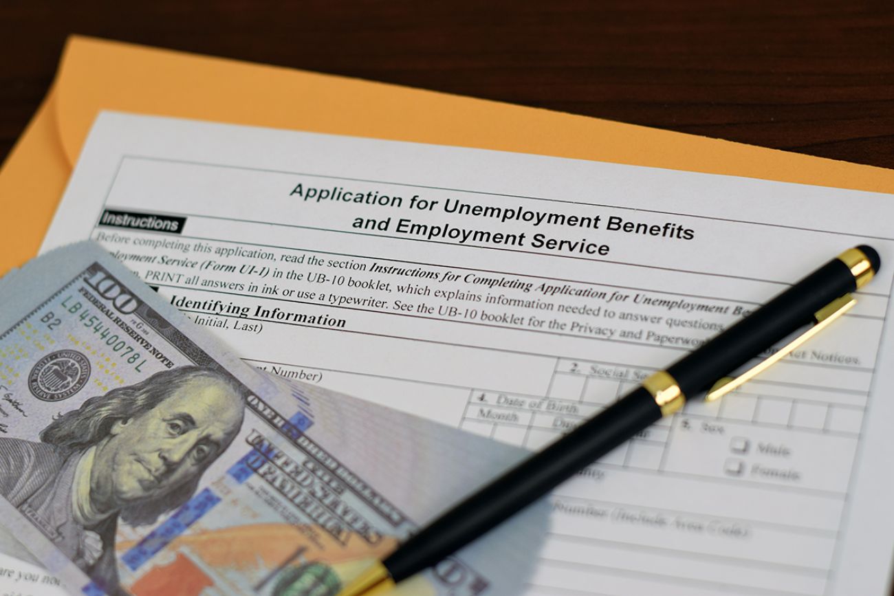 Cash, pen and an application for unemployment benefits 