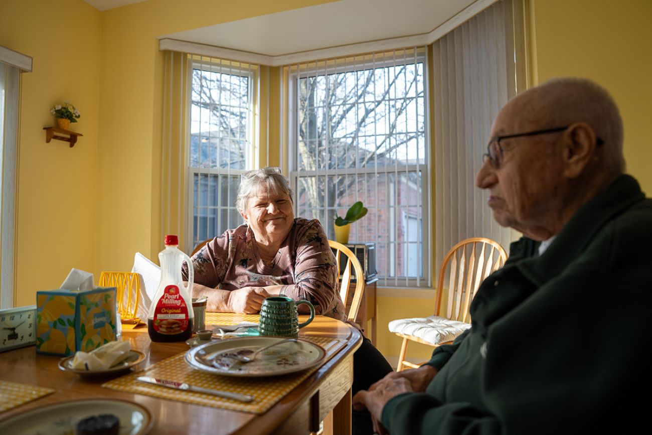 Two older people sitting at a kitchen table.