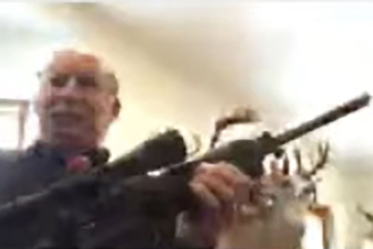 A blurry photo of Grand Traverse County Commissioner Ron Clous holding a rifle.