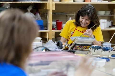 Margaret Afheldt smiles as she glazes a bowl. 