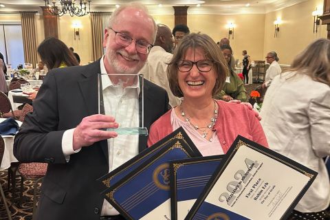 Ron French and Robin Erb smile and hold awards. 