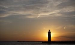 The sunset from Pere Marquette beach in Muskegon, Michigan. You can see a lighthouse.