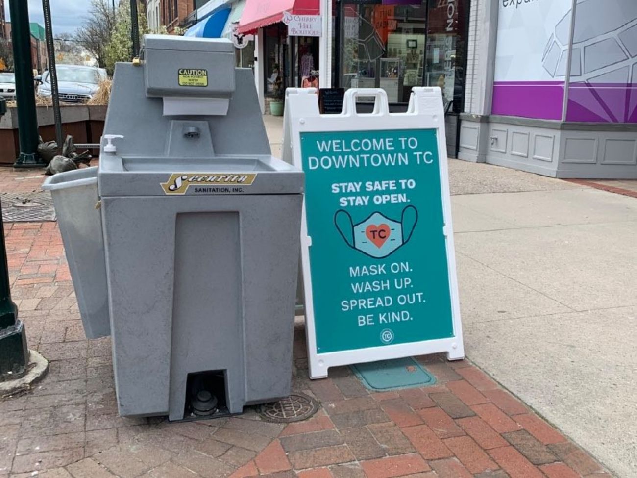 A hand sanitizing station and sign asking tourists to take health precautions