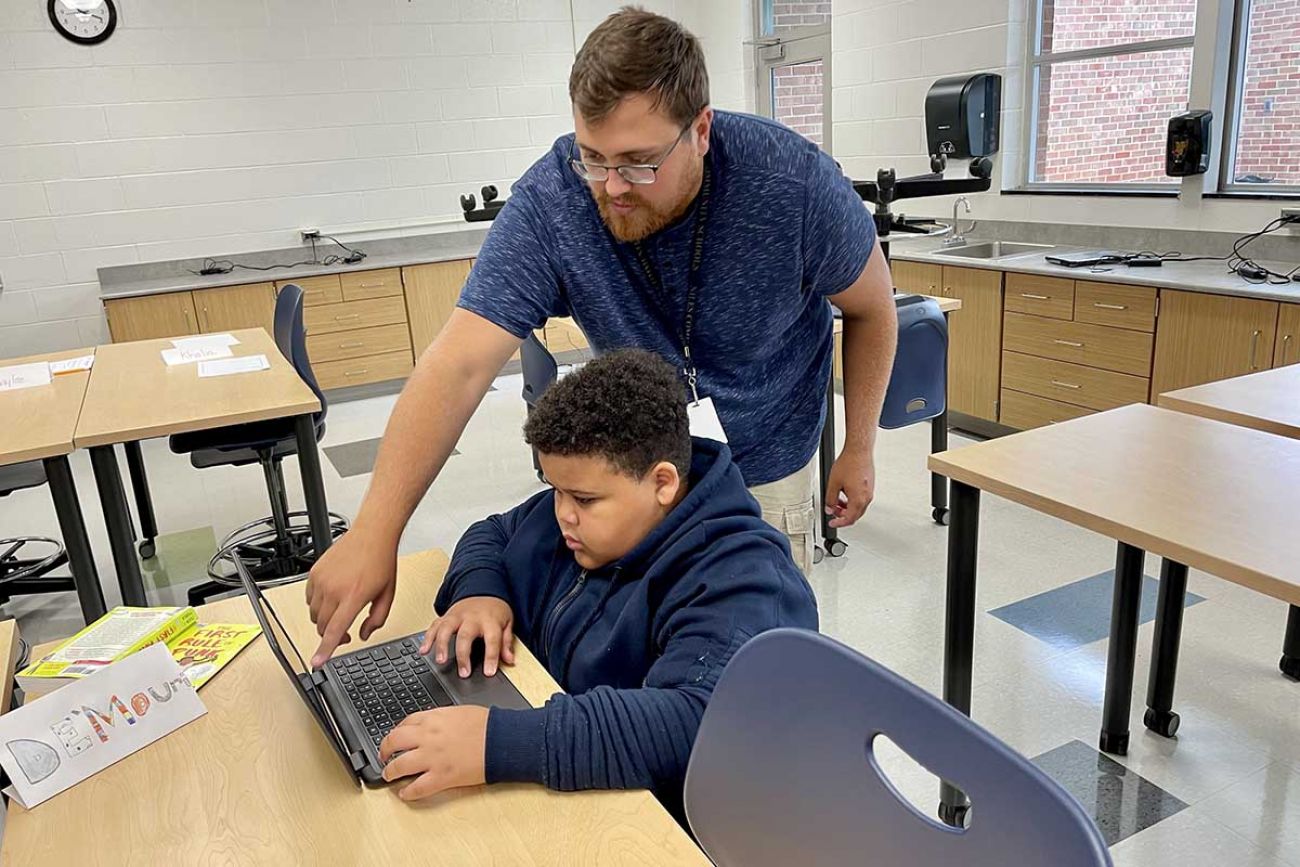 Teacher Adam Roark helping De’Mauri Dotson in classroom