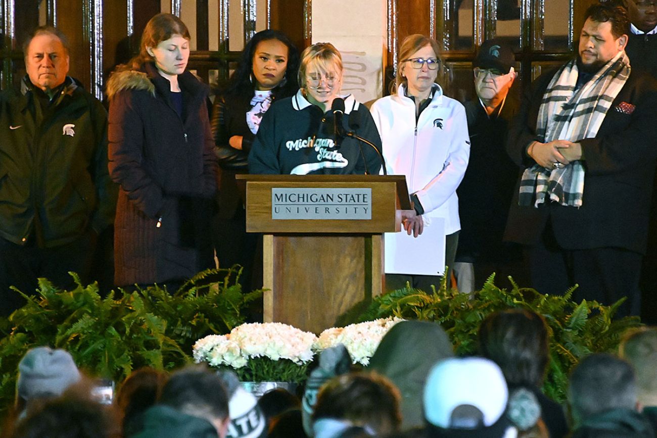 Jo Kovach at a podium surrounded by student