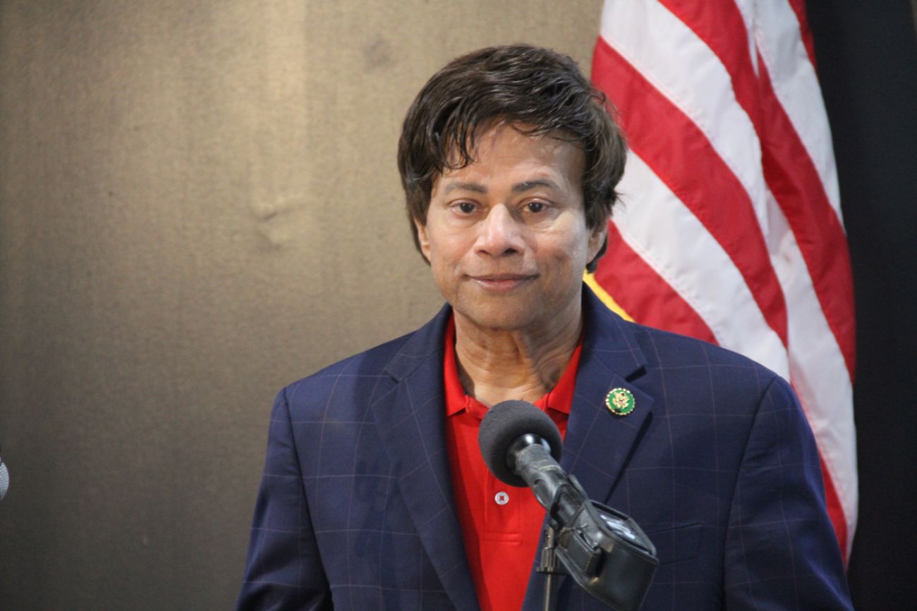 Man stands in front of flag at a podium