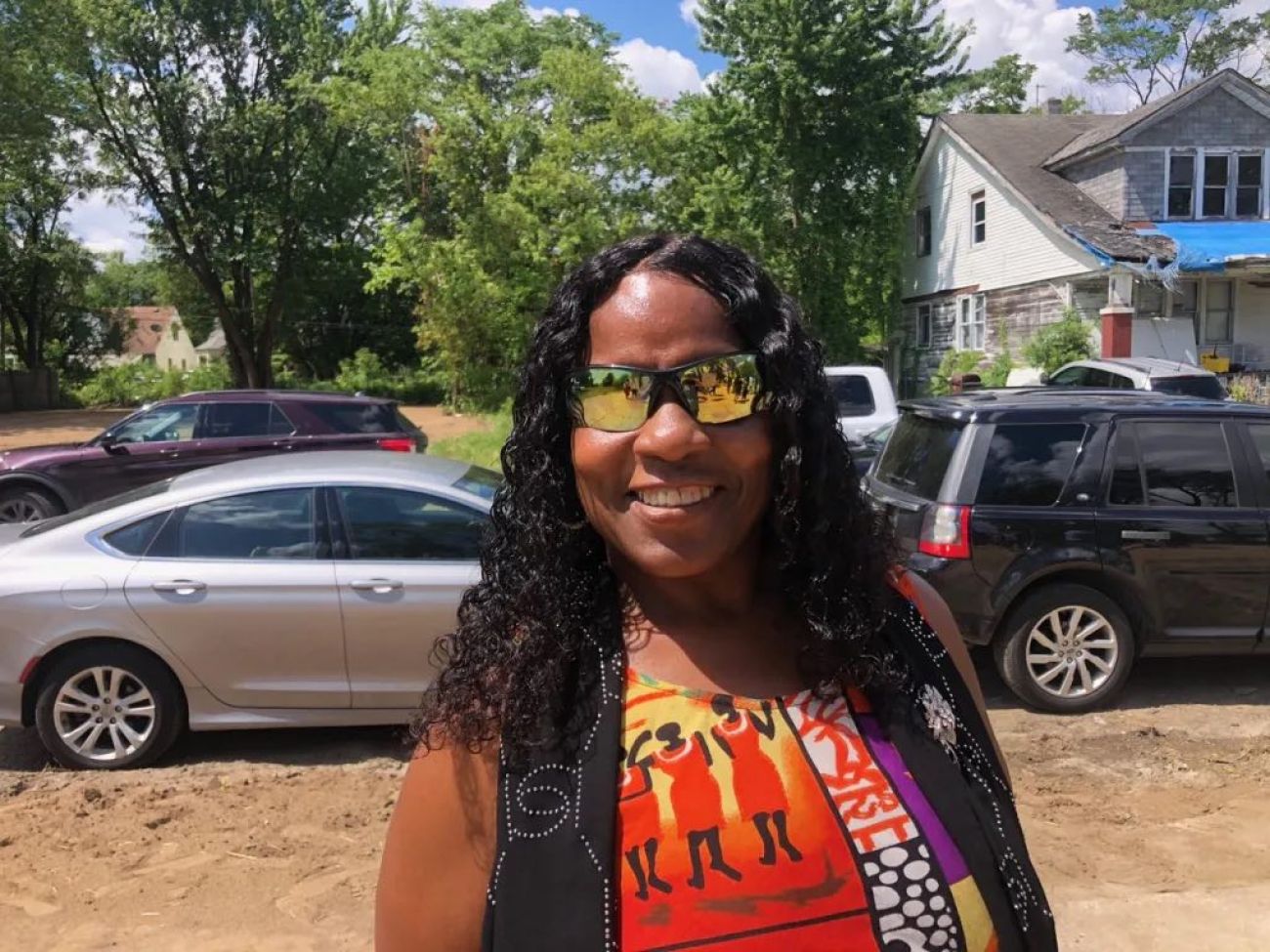 Donna Anthony, wearing a multi-colored shirt, stands outside.