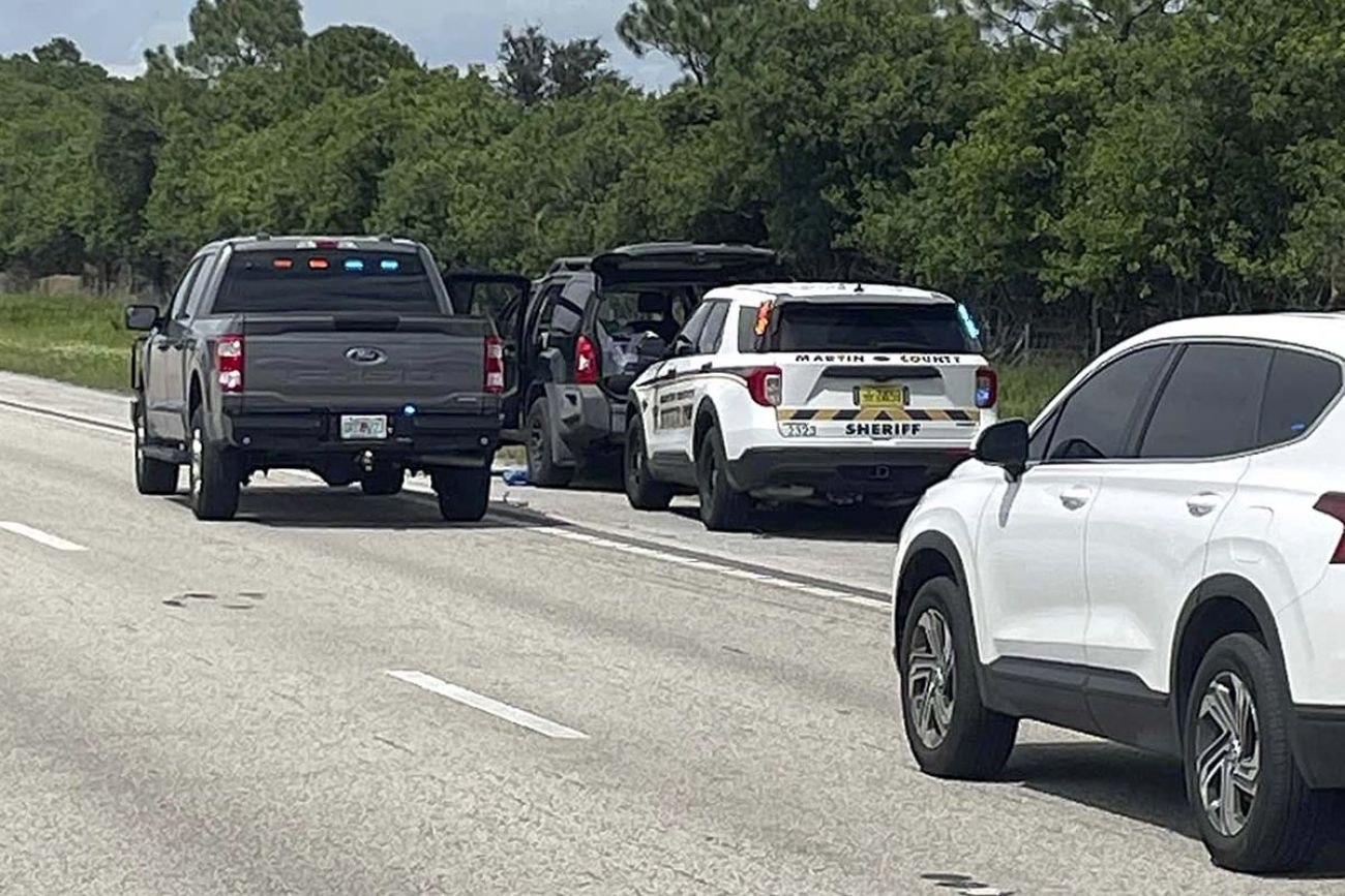 Police vehicle surrounding a black SUV on the side of the road