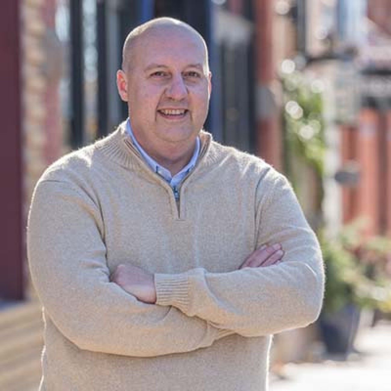 Curtis Hertel Jr. wearing a tan sweatshirt, posing for a picture