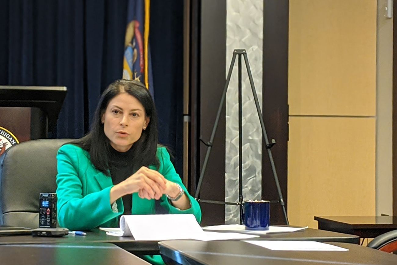 Attorney General Dana Nessel sits a table