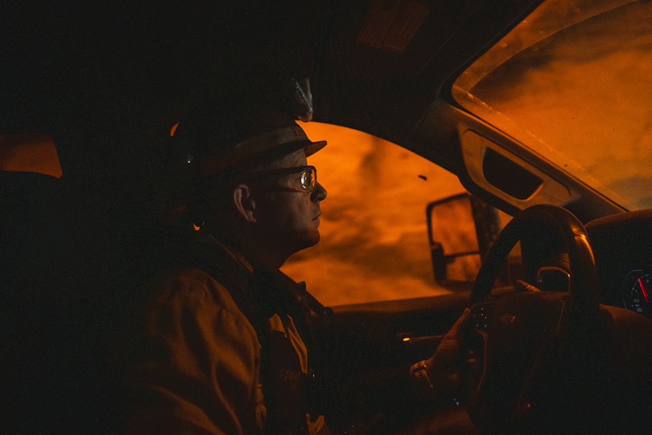 Andy Vaughn driving a pickup truck. The nickel and copper mine looks orange