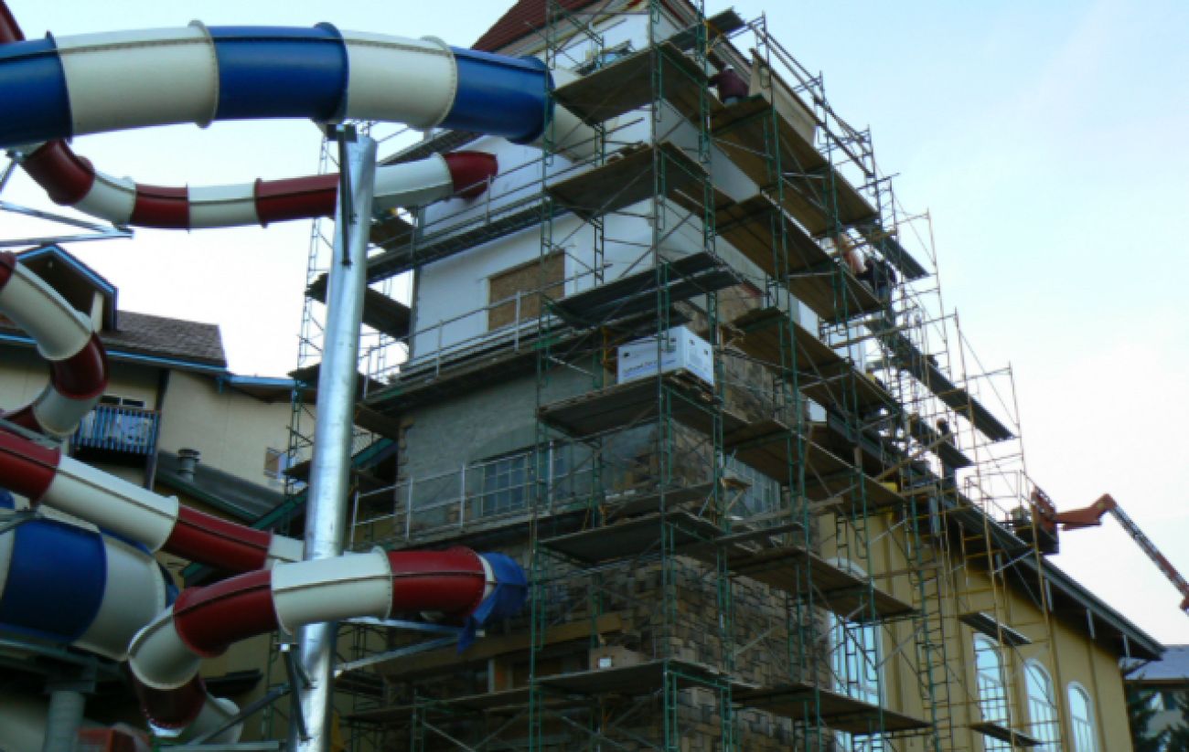 A red, white, blue waterslide coming out of building