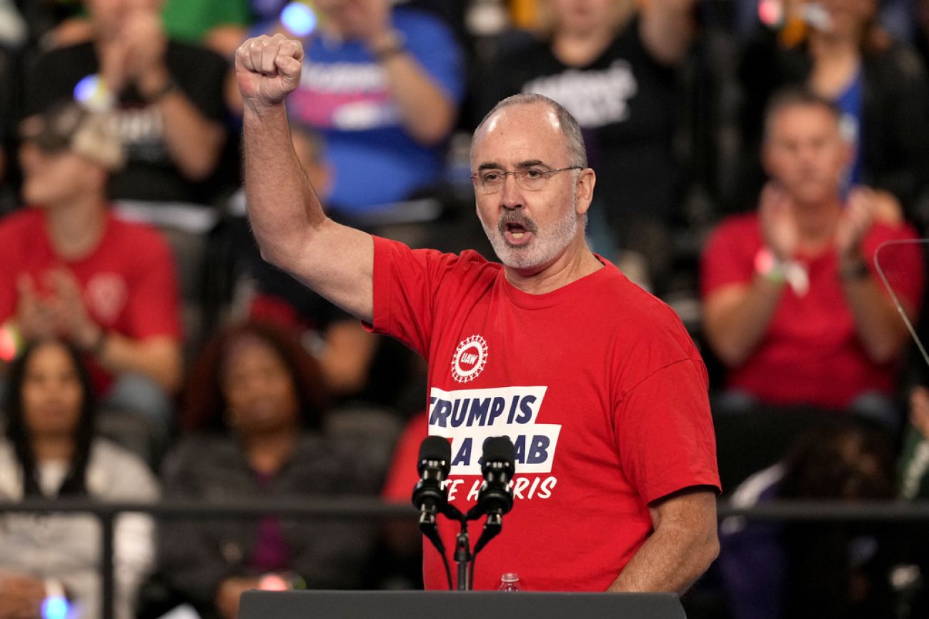 Shawn Fain raises his first in the air at a rally in Flint, Mich.