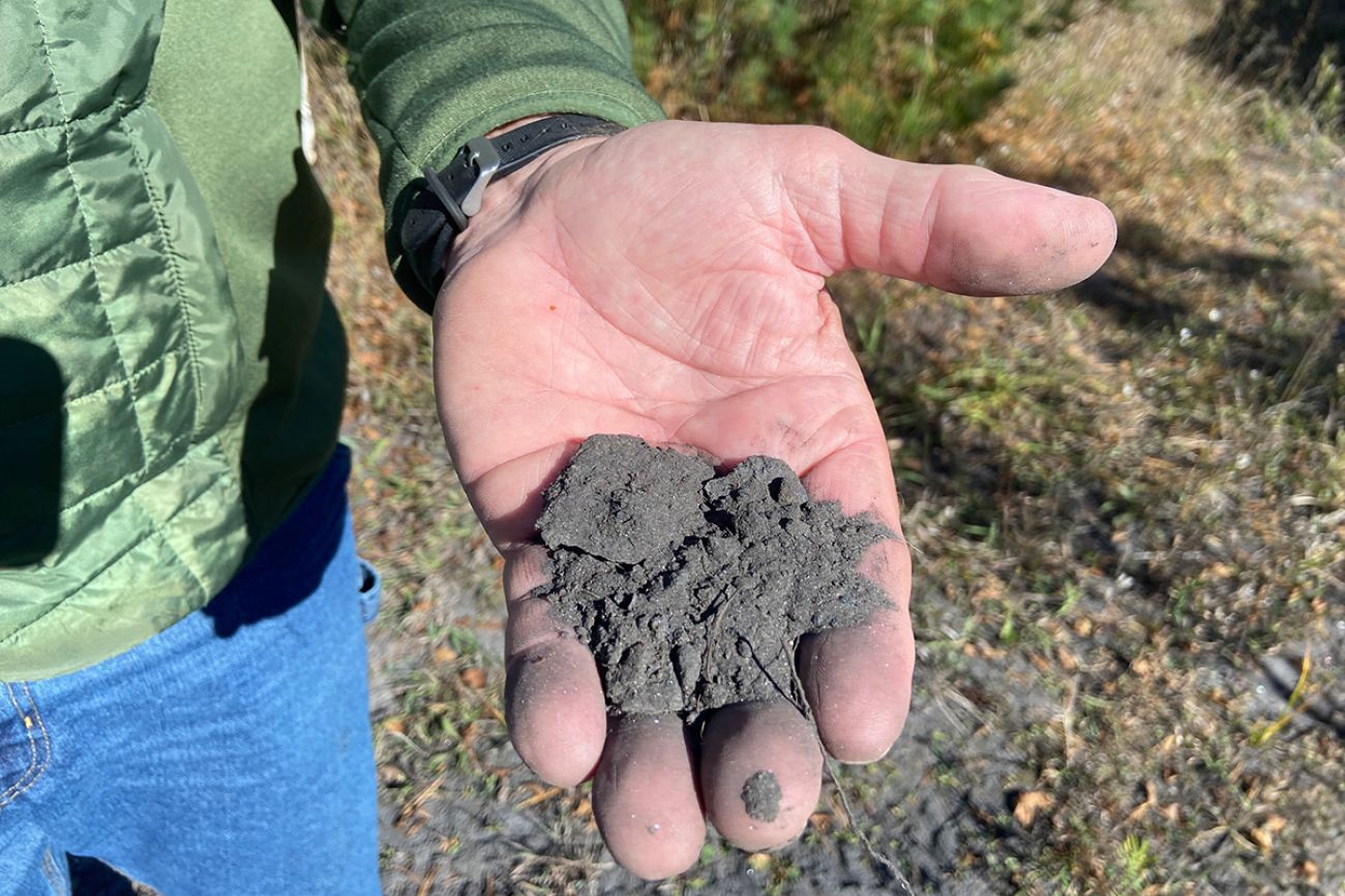 A close up a hand that has a pile of mine tailings, which looks like clumpy dirt