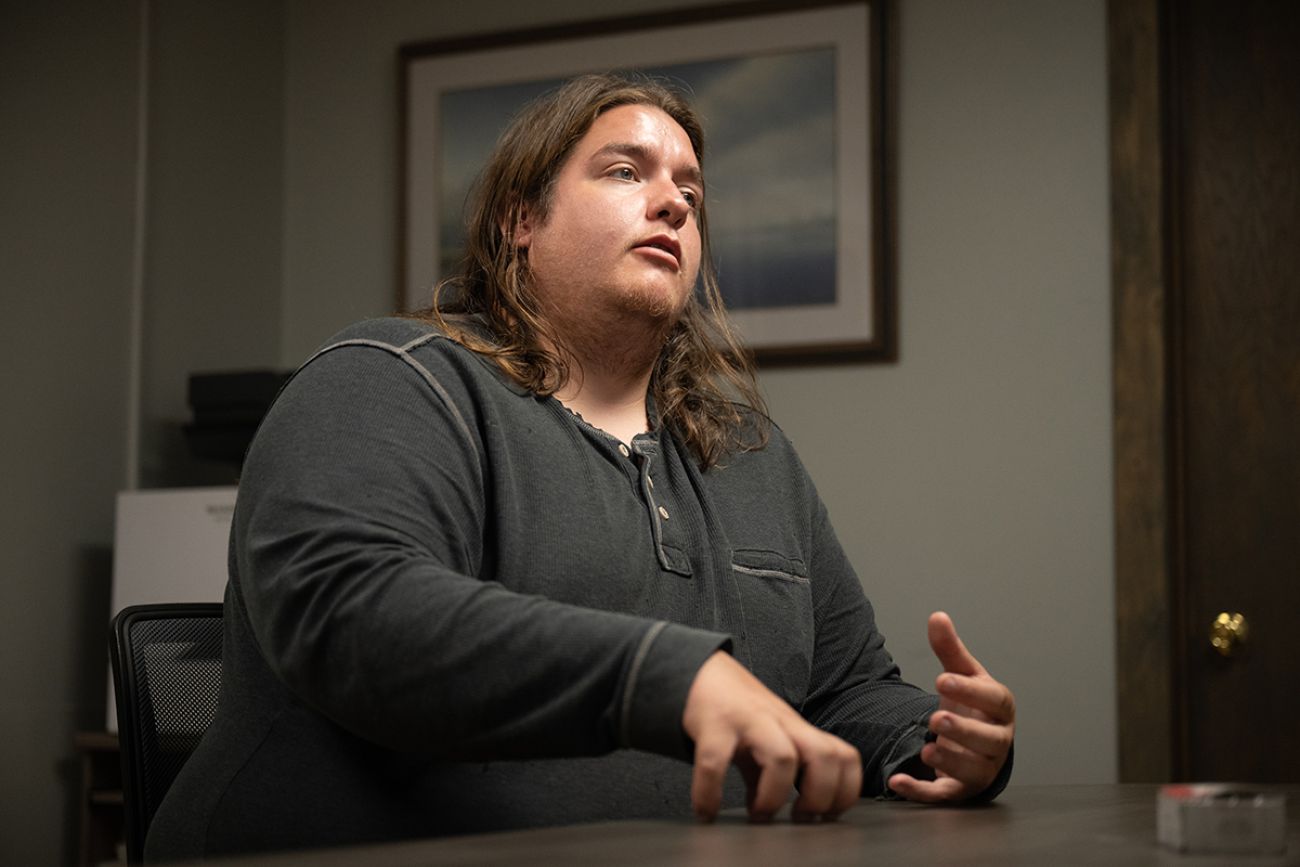 Theodore ‘Austin’ Ayres, wearing a long sleeve shirt, sits at a a table