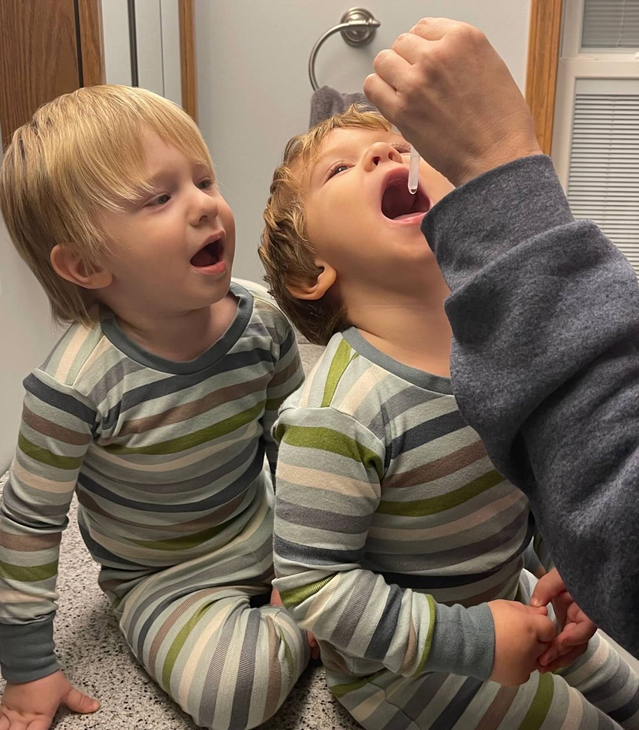 Two blonde toddler getting fluoride drops