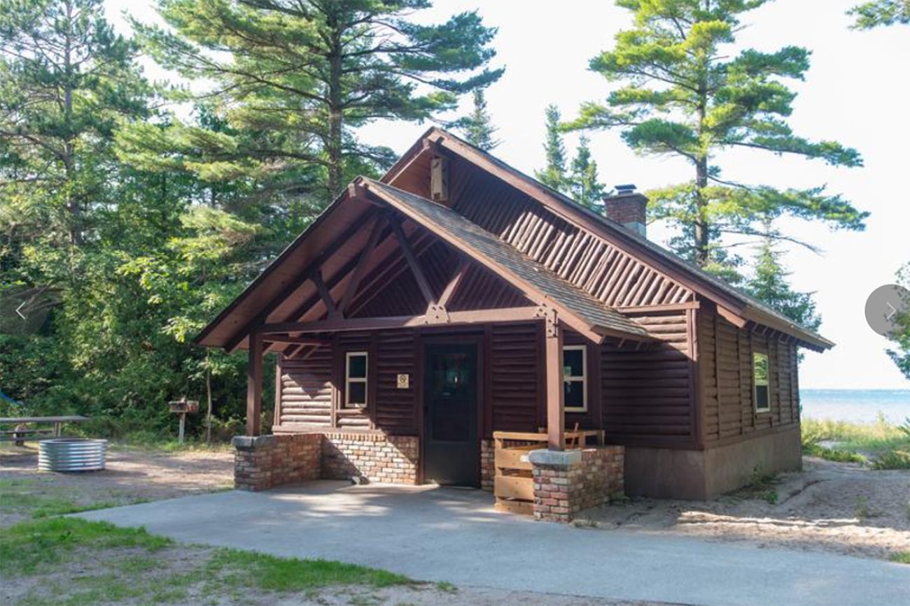 A red cabin in front of a lake. 