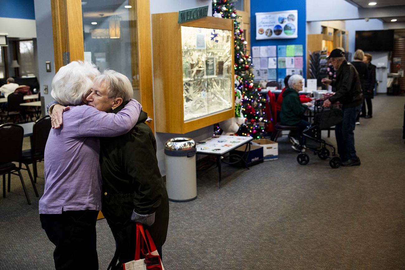 Two mature women hug each other at the Clinton Township Senior Center