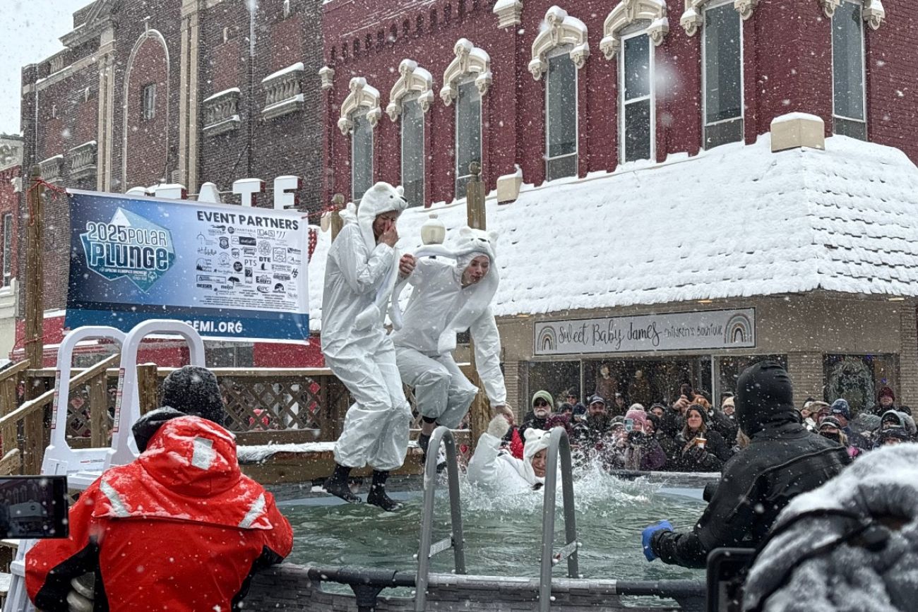 Three people jump in a pool in snowy Alpena, Michigan. 