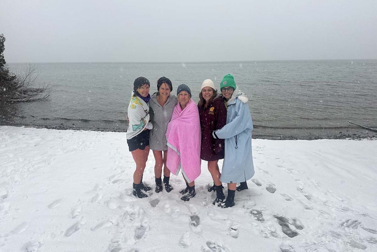 A group of women pose for a picture. They are in the snow. 