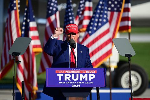 Trump campaigning in Michigan, wearing a blue suit and MAGA hat