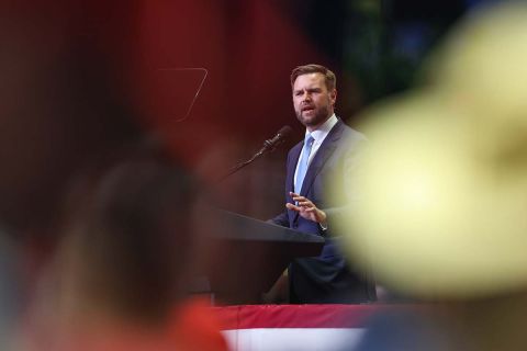 JD Vance, wearing a blue suit, speaks into a microphone