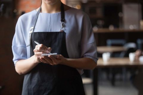 Woman cafe worker with notebook in hands waiting for an order