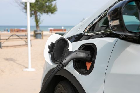 White EV car being charged at the beach