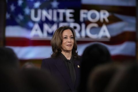 Kamala Harris on the stage, behind the stage says Unite for America