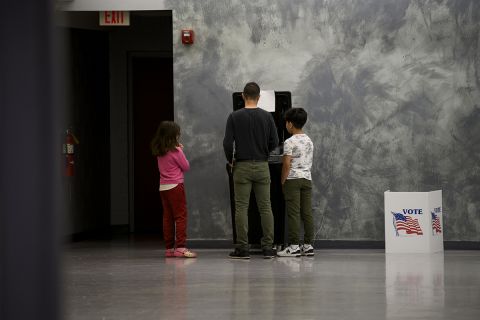 A voter casts a ballot at Owen Jax Community Center in Warren, Mich. Two kids stand next him