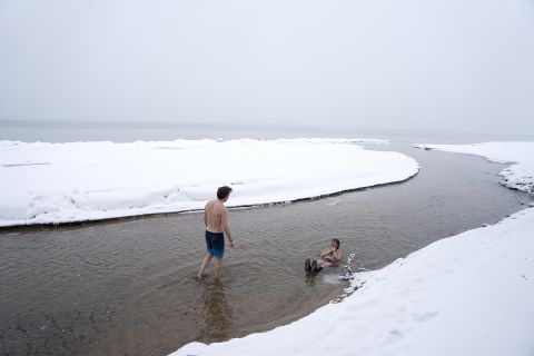 Two people in East Bay of Grand Traverse Bay in Michigan. It's snowy and icy outside. 