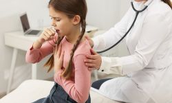 Doctor examining coughing girl in hospital