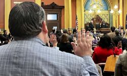 Michigan lawmakers hold their hand up during swearing ceremony