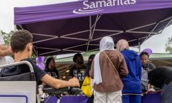 People approach a purple Samaritas tent. 