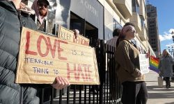 Someone holding a sign that says "Love is a terrible thing to hate," 