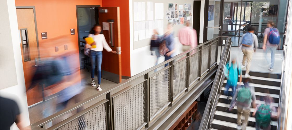 Busy high school corridor with blurred students and staff